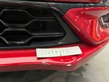 a close up of the front of a red car with a sticker on it