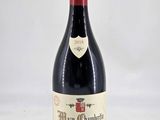 the bottle of red wine is sitting on a white surface