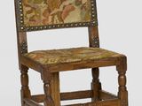 une vieille chaise en bois dont l'assise et le dossier sont recouverts d'un tissu coloré