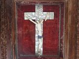 painting of a crucifix in a wooden frame with a red background