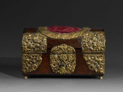 an antique wooden box with gold decorations and a red cloth