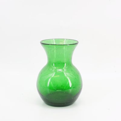un vase en verre vert posé sur une surface blanche