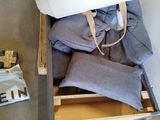 a wooden crate filled with clothes and a white pillow