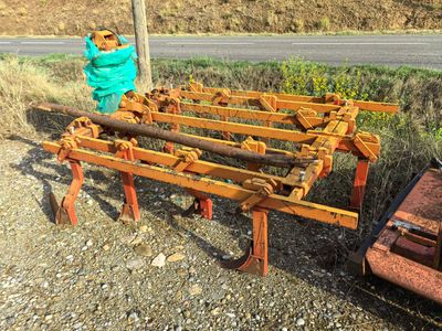 a tractor and a plow sitting on the side of the road