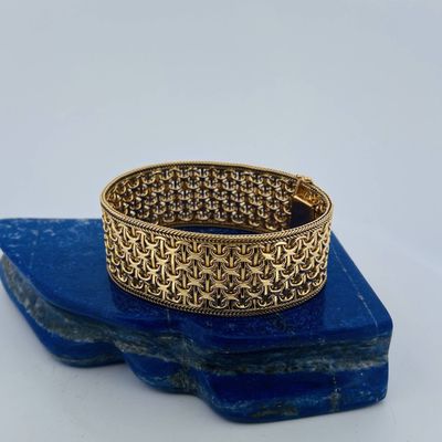 un gros plan d'un bracelet en or posé sur une pierre bleue