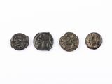 un ensemble de quatre pièces de monnaie romaines antiques posées sur une surface blanche