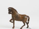 a small wooden horse that is standing on a white surface