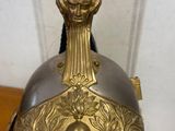 a person holding a silver and gold helmet on a table