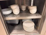 many plates and bowls stacked on the shelves in the kitchen