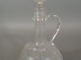 a clear glass bottle with a handle on a table