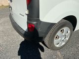 une camionnette blanche garée sur un parking à côté d'un bâtiment
