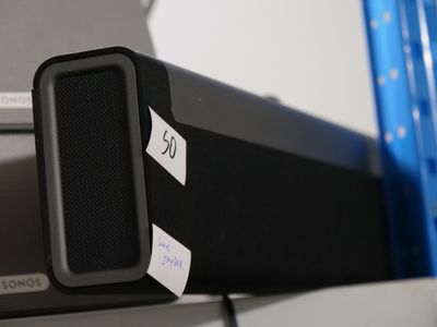 a black speaker sitting on top of a shelf next to a laptop