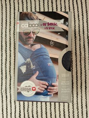 Le porte-bébé se trouve dans la boîte posée sur la couverture rayée.