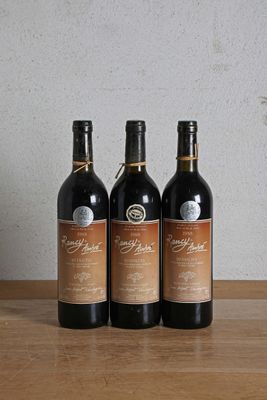trois bouteilles de vin posées sur une table en bois, à côté d'une bouteille de vin