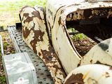 a rusted old car sitting in the grass