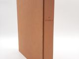 une image représentant un livre marron posé sur une surface blanche