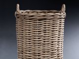 a large wicker basket with handles on a grey background