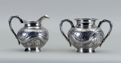 deux vases en argent munis d'anses, posés sur un fond blanc