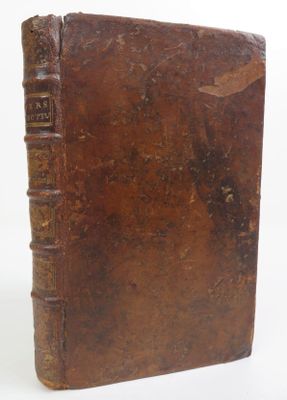 an old brown book sitting on top of a table next to a white wall