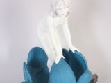 une figurine posée sur une fleur bleue