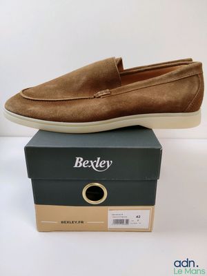 une paire de chaussures en daim marron posée sur une boîte
