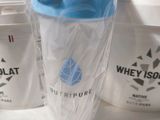 a plastic cup with a blue lid sitting next to a container of whey island