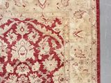 an antique rug with a red and beige design on a grey background