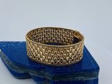un gros plan d'un bracelet en or posé sur une pierre bleue