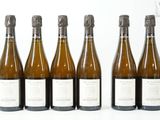 six bouteilles de vin sont alignées sur une surface blanche