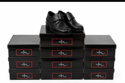 four black boxes with black shoes on top of them on a white surface