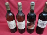four bottles of wine are lined up on a red cloth