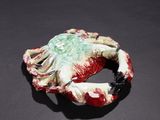 a close up of a red and green crab on a black surface
