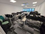 des rangées de bureaux et de chaises d'informatique dans une grande salle ouverte