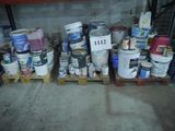 de nombreux seaux de peinture posés sur les palettes dans le garage