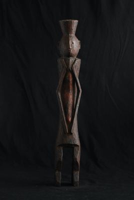 une sculpture en bois représentant une personne debout sur un fond noir