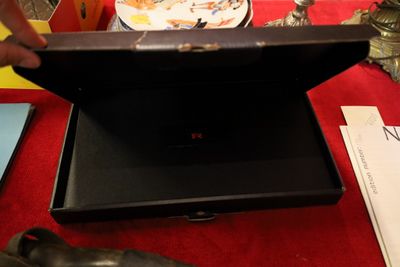 a man opening a briefcase on a table with a plate of food in the background