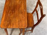a small wooden table and two chairs on the sidewalk