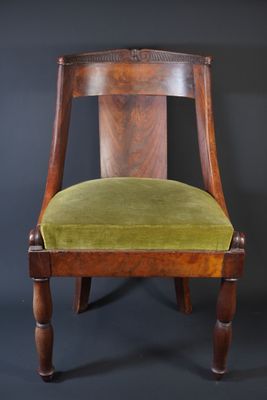an old chair with a green velvet seat on a black background