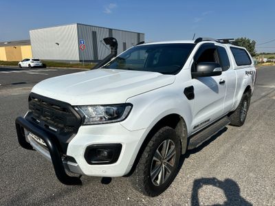 the white ford ranger is parked on the side of the road