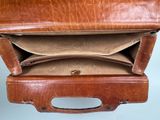 a brown leather suitcase with a handle and two compartments
