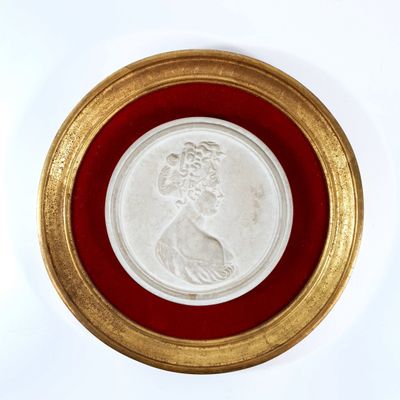 an image of a gold and white medallion with a woman ' s face