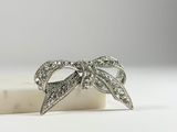 a close up of a diamond bow brooch on a marble block