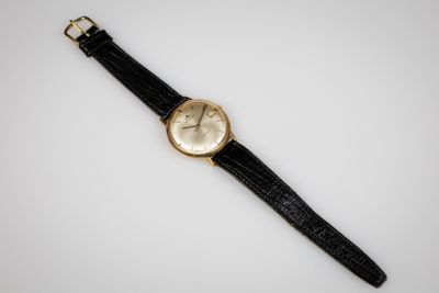 une montre en or avec un bracelet en cuir noir et un cadran blanc
