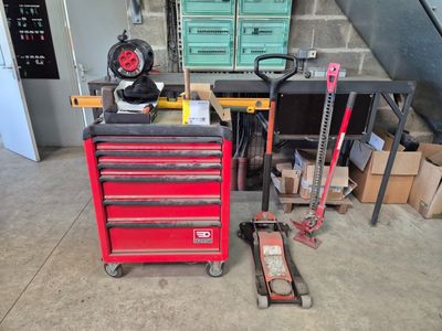 une boîte à outils rouge sur laquelle sont posés des outils, dans un garage