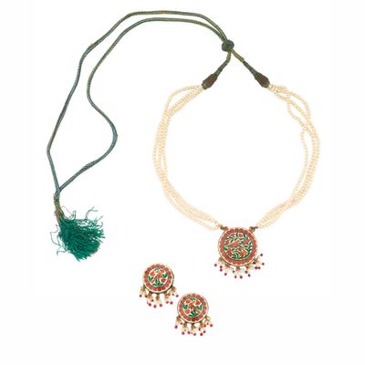 a close up of a necklace and earrings on a white background