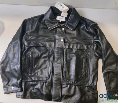 une veste en cuir noir posée sur une table blanche