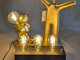 a gold statue of a man holding a light bulb and a lamp