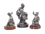 trois figurines en argent représentant une femme et un enfant, posées sur des socles en marbre