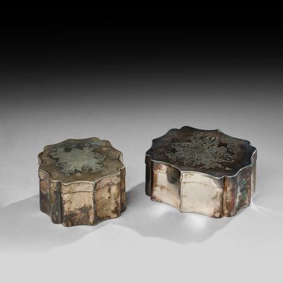 deux boîtes argentées posées l'une à côté de l'autre sur une surface blanche