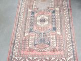 un vieux tapis aux motifs rouges et bleus posé sur un sol gris